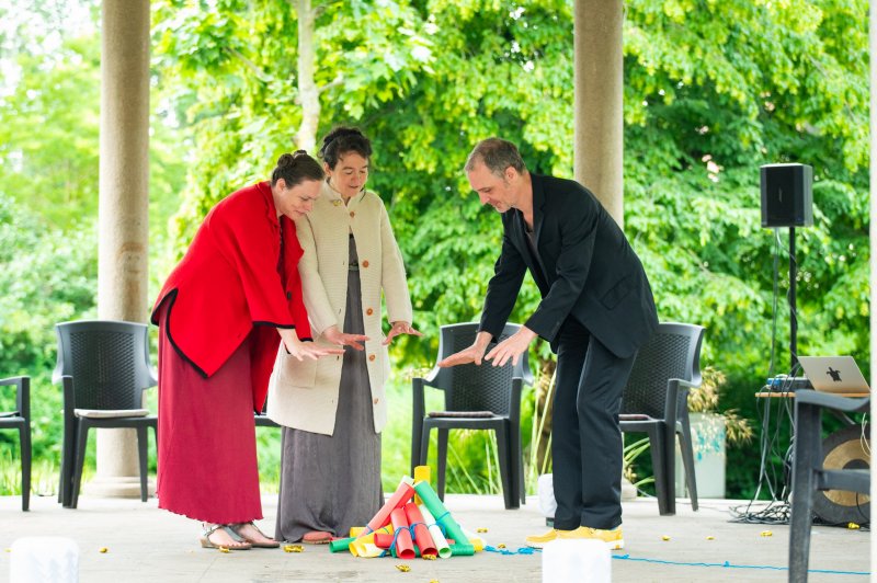 Drei Schauspieler:innen wärmen sich am „Lagerfeuer“ aus Schriftrollen