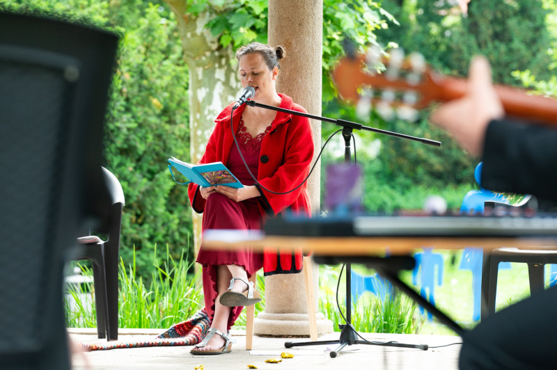 Beate Krist liest aus einem Märchen, im Vordergrund ragt der Kopf einer Gitarre unscharf ins Bild